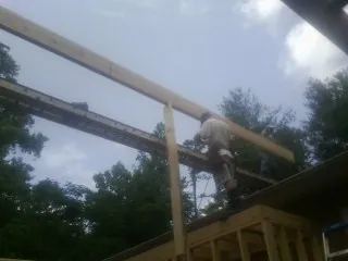 Carpenter setting a ridge beam over a new addition frame — Ice Dam Removal by Roofing Brothers in Crosby