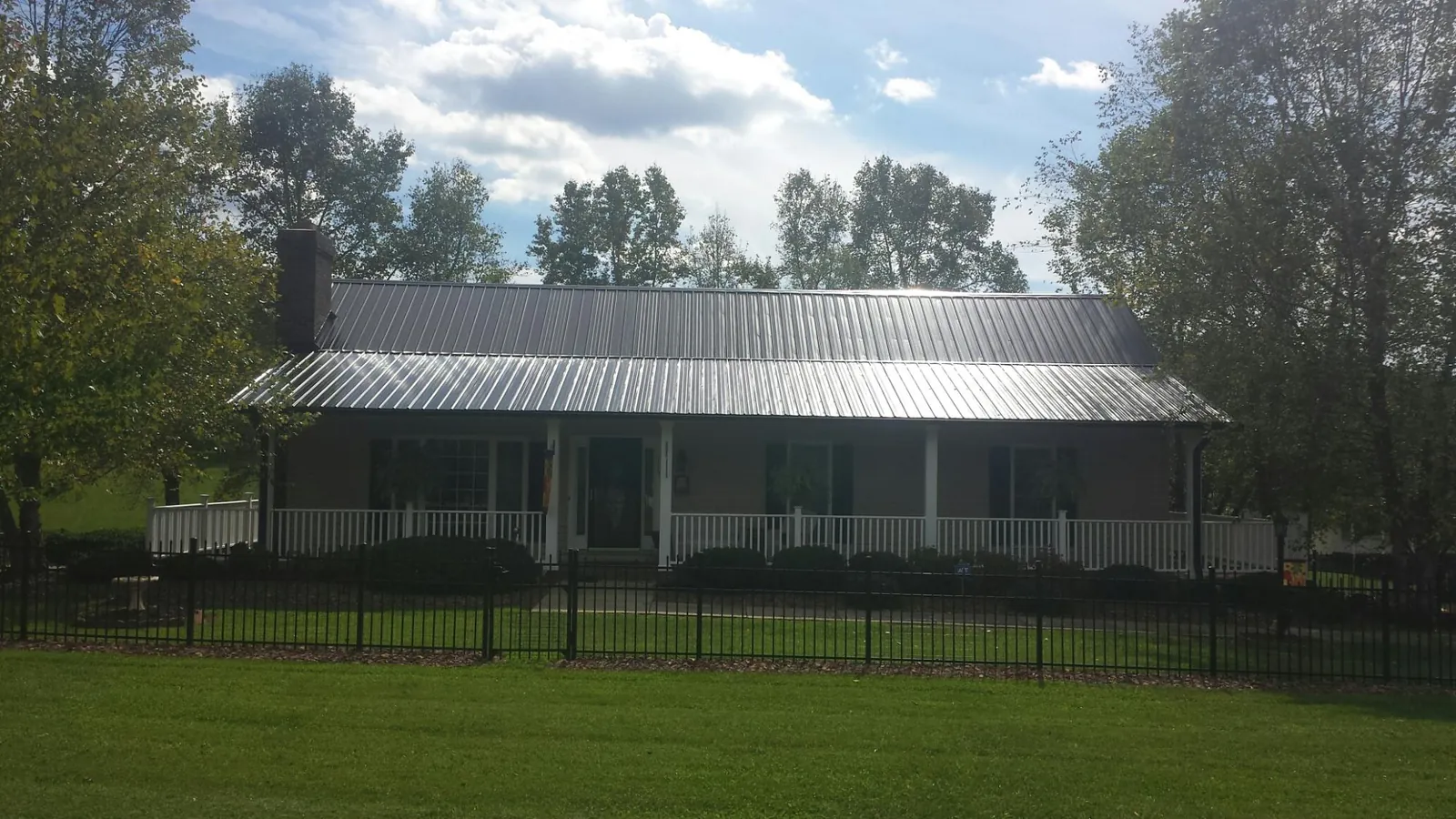 Gray metal roof on a brick ranch with a full width front porch — Gutter Guard Installation work by our crew in Crosby